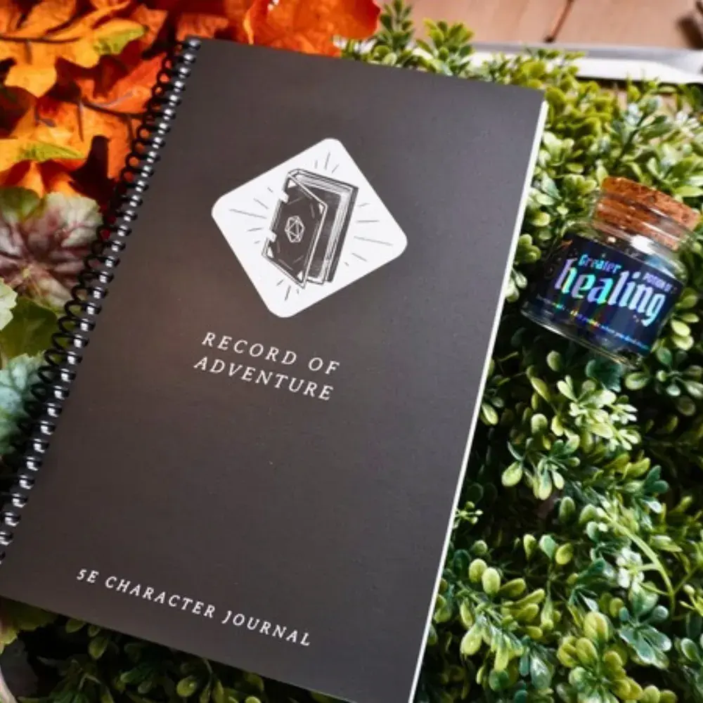 Black Record of Adventure 5e character journal next to a Potion of Greater Healing dice bottle on a bed of greenery
